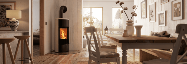 Ein Kaminofen steht in der Ecke eines hell eingerichteten Essbereiches und dient als Raumteiler zum Wohnzimmer.