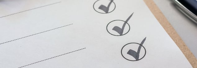 Papier-Formular mit drei abgehakten Kontrollkästchen auf einem Klemmbrett