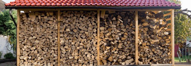 Überdachtes Holzregal mit gestapelten Holzscheiten.