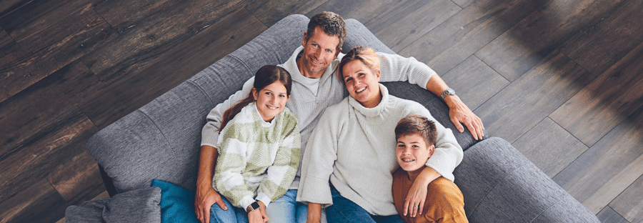 Familie Jachens liegt gemeinsam auf einer grauen Couch.