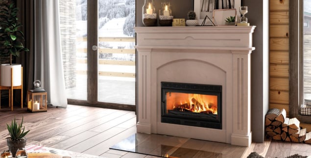 Kaminkassette mit weißer Marmorverkleidung im modernen Wohnzimmer mit Holzscheiten und Blick in die Winterlandschaft