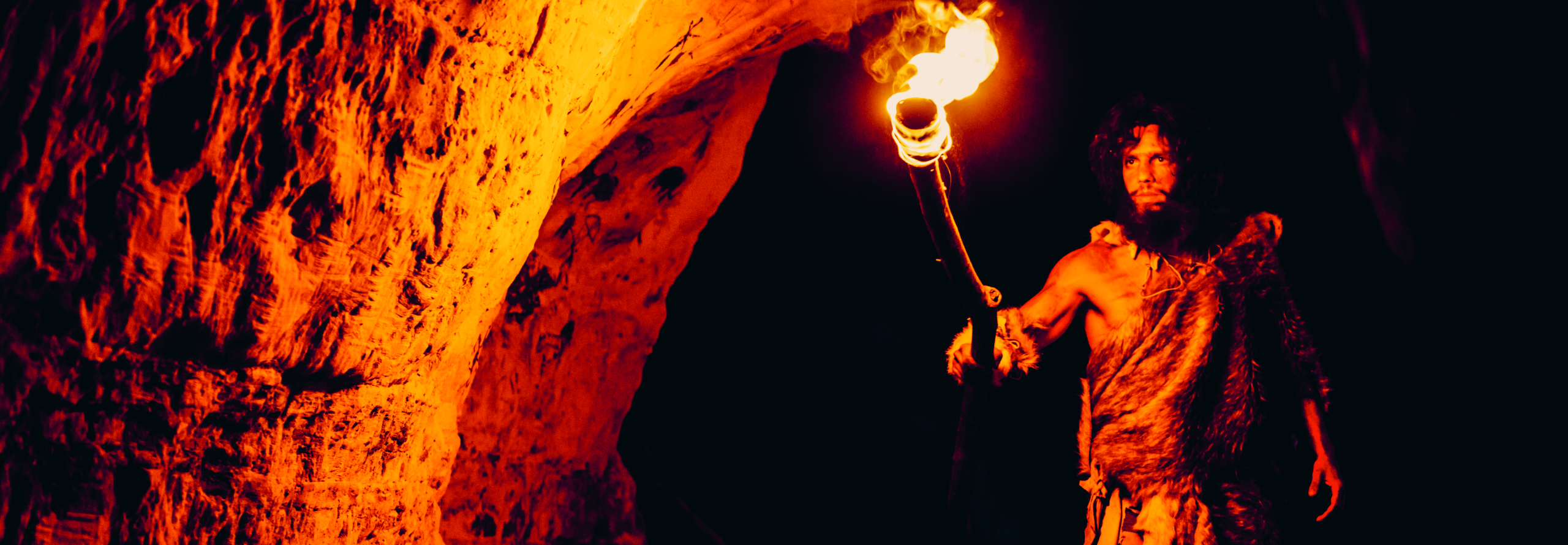 Bild eines Menschen vor ungefähr einer Million Jahren mit einer Fackel in der Hand in einer Höhle.