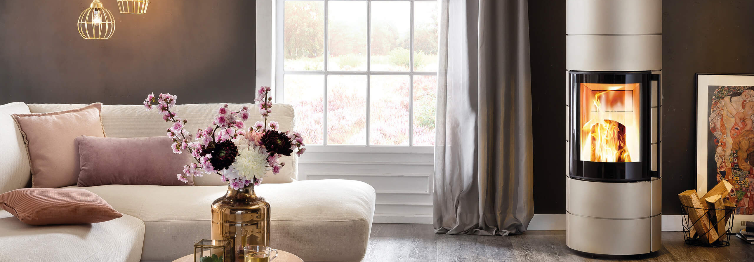 Silberner Kamin steht rechts vom Sofa mit Ausblick in den Blumengarten