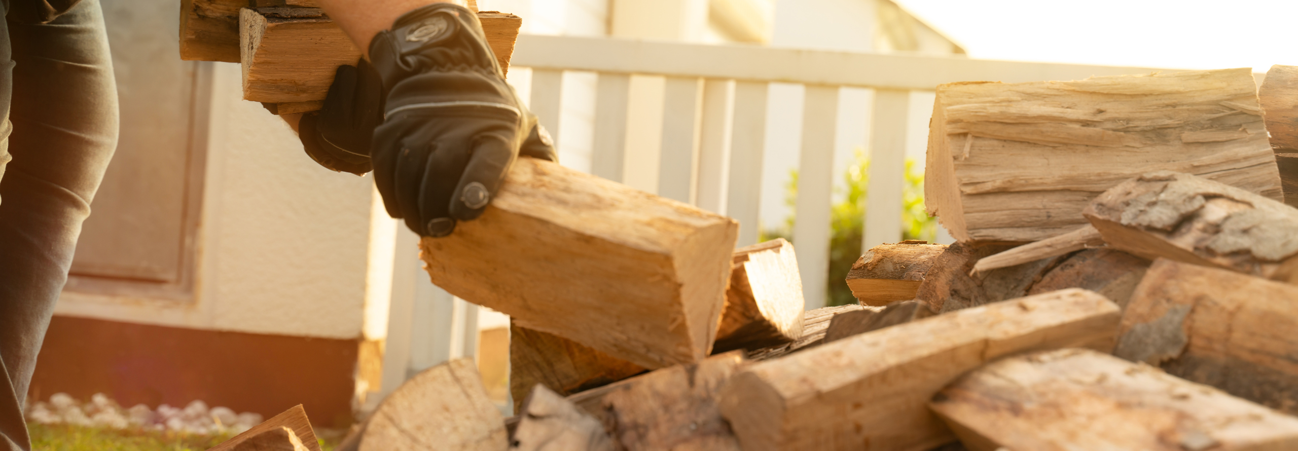 Person mit Handschuh greift nach Brennholz